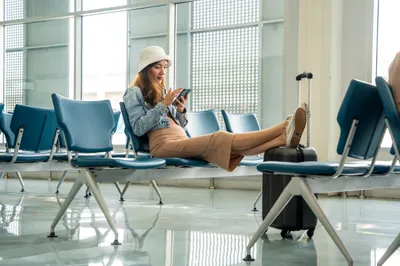 frau sitzt im wartebereich am flughafen