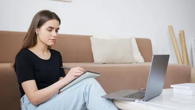 frau mit stift und notizblock sitzt auf dem boden