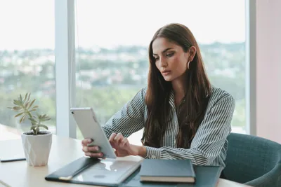 frau mit tablet in der hand sitzt am fenster