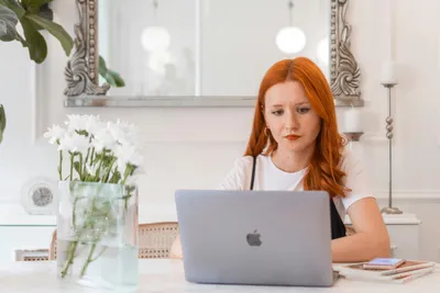 frau mit roten haaren sitzt am laptop