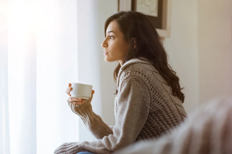 frau denkt nach mit tasse in der hand