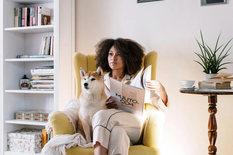 frau sitzt auf dem sessel mit zeitung und hund