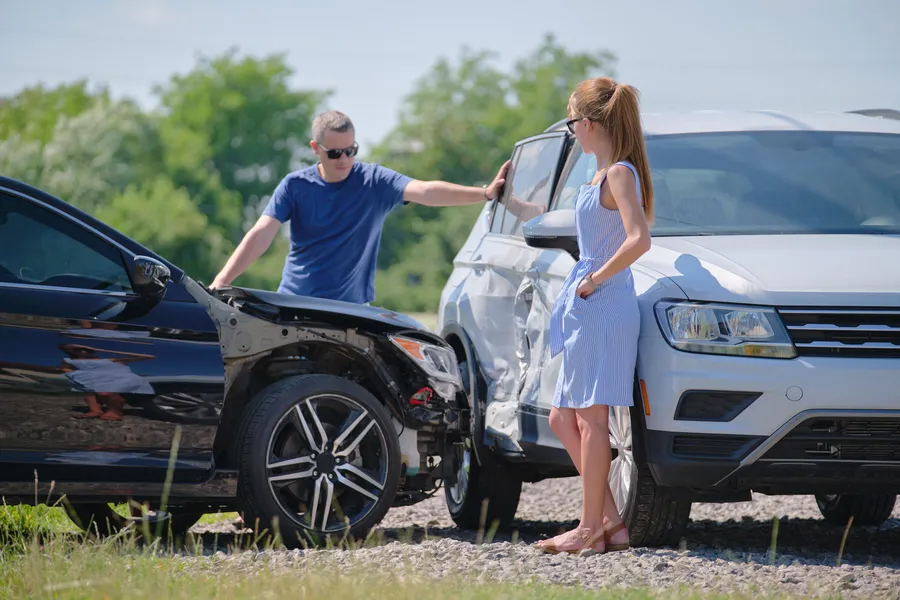 zwei personen schauen sich den schaden an ihren wagen an