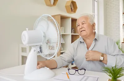 mann sitzt am schreibtisch mit ventilator