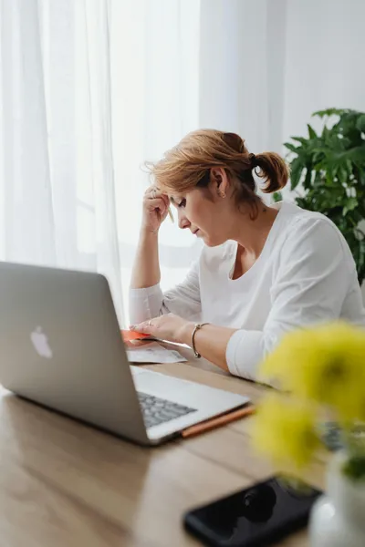 frau am schreibtisch mit laptop und stift in der hand