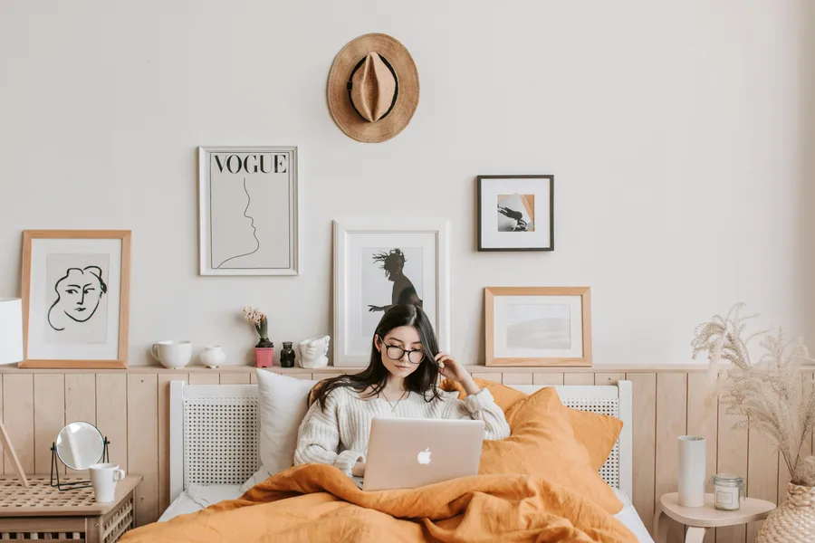 frau liegt im bett und schaut auf den laptop