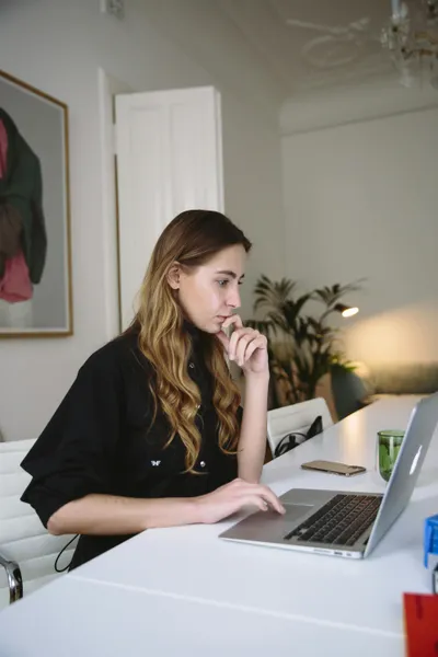 frau sitzt am schreibtisch und recherchiert am laptop