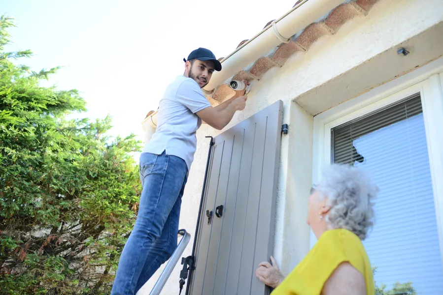 mann installiert kamera am haus