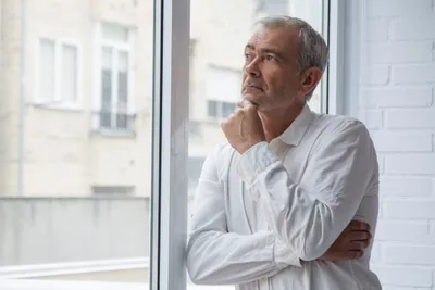 mann steht am fenster und denkt nach