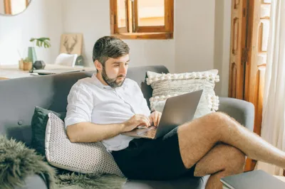 mann sitzt auf dem sofa mit laptop