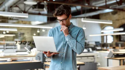 mann hält laptop in der hand und schaut darauf